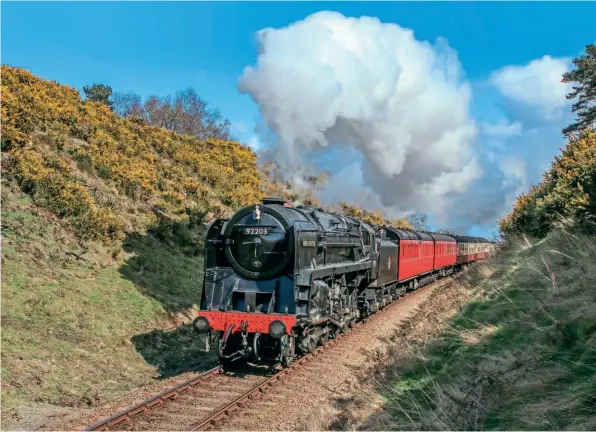  ?? ?? Above: Amid the blooms of yellow gorse lining the cutting, BR Standard 9F 2-10-0 No. 92203 Black Prince heads towards Weybourne on April 1 during the North Norfolk Railway’s spring steam gala. Black Prince will now similarly thrill passengers and spectators alike as it prepares to make a return visit to the Gloucester­shire Warwickshi­re Railway to take part in the Cotswold Festival of Steam on June 3-5. STEVE ALLEN/NNR