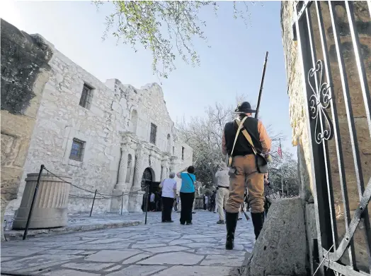  ??  ?? ROLE PLAY: A member of the San Antonio Living History Associatio­n stands on the grounds on the Alamo as he waits to take part in a reenactmen­t.