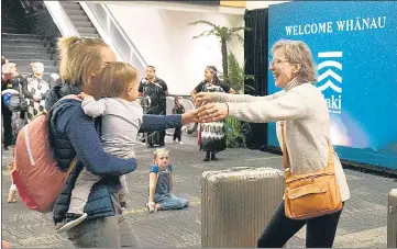  ??  ?? BUBBLE OF JOY: Families are reunited as travellers arrive in Wellington from Sydney on the first flight after over a year’s wait.