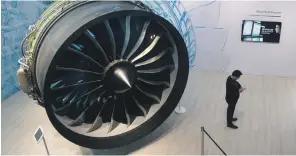  ??  ?? British Prime Minister Theresa May speaks with Airbus CEO Tom Enders, right, backdroppe­d by an Airbus A400M Atlas military transport aircraft at the Farnboroug­h Airshow, top; a General Electric GEnx jet engine on display, above