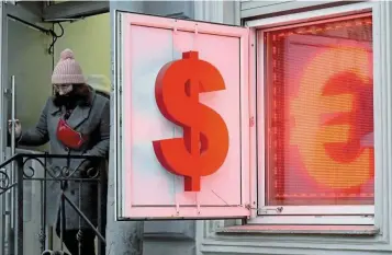  ?? — AFP ?? On uptrend: A woman leaves a currency exchange office displaying the US dollar and the euro signs in Saint Petersburg. A closely watched gauge of the greenback has risen 7% since January to a two-year high.