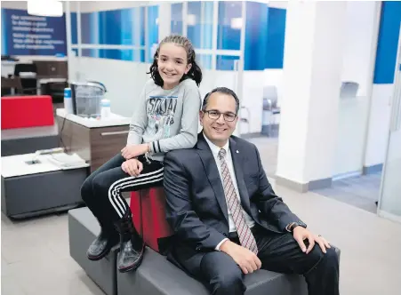  ?? JUSTIN TANG, THE CANADIAN PRESS ?? Bank of Montreal regional vice-president Omar Abouzaher sits with his daughter Yasmina, 11, in an Ottawa branch. Abouzaher says some parents wait too long to teach their kids financial literacy.