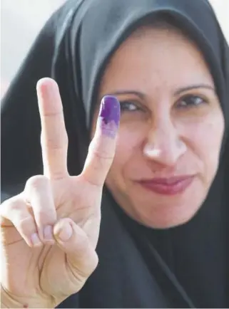  ?? Andrew Parsons, Associated Press file ?? An Iraqi woman holds up her hand and shows a purple finger, indicating she has just voted, as she leaves a polling station in Az Zubayr, southern Iraq, on Jan. 30, 2005. Iraqis were voting in their country’s first free election in a half-century.