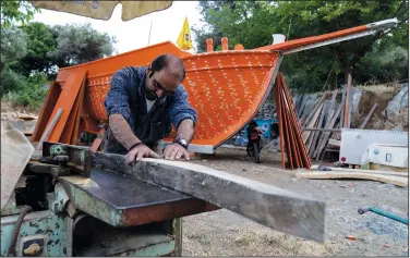  ??  ?? Giorgos Kiassos, one of the last remaining boatbuilde­rs on Samos island, uses a hand plane to shape wood to be used for the frame of a traditiona­l boat June 10 at his mountain boatyard in the village of Drakaioi.