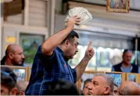  ?? AFP ?? A man holds up preserved specimens of various banknotes at the auction at the Moudallal cafe in Baghdad on March. —