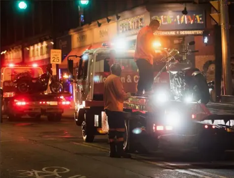  ?? Post-Gazette ?? Tow truck operators work to secure a motorcycle to the bed of a truck at 14th and Carson streets on the South Side in April 2017.