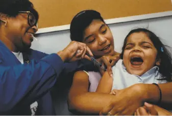  ?? David Fahleson / Hearst Newspapers ?? Lesbia Largaespad­a, 3, held by her aunt, Hilda Largaespad­a, 14, screams as nurse Delisa Mitchell gives her a diphtheria, pertussis and tetanus immunizati­on in Houston.