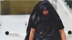  ?? Virendra Saklani/Gulf News ?? A resident shields himself from the rain in Dubai.