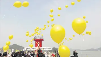  ?? REUTERS ?? People release yellow balloons dedicated to the victims onboard the sunken ferry ‘Sewol’ during an event at a port in Jindo, South Korea.