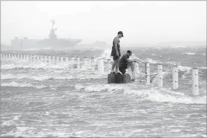  ?? ERIC GAY AP ?? Two men stand near a sea wall as Hurricane Hanna makes landfall Saturday in Corpus Christi, Texas. The first hurricane of the 2020 Atlantic hurricane season made landfall twice on Saturday afternoon within the span of little over an hour.