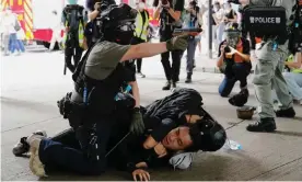  ?? Photograph: Tyrone Siu/Reuters ?? A police officer raises his pepper-spray gun as he detains a man in Hong Kong.