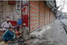  ?? Photograph: Abdul Majeed/AFP/Getty ?? A cobbler drinks tea with friends beside shuttered stores in Peshawar after many Pakistani traders shut up shop in protest.