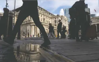  ?? CHRIS RATCLIFFE/BLOOMBERG ?? Workers pass the Bank of England in London on Thursday. U.K. Prime Minister Liz Truss faults the Ukraine war and COVID for doing economic damage in the U.K. while critics blame her policies.