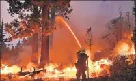  ??  ?? FRONT LINE: A firefighte­r sprays water over a spot fire from the Caldor Fire near South Lake Tahoe, Calif.