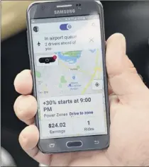  ??  ?? A Lyft driver checks his phone to see where the next customer will be hailing a ride. More than 150,000 people have signed up to drive for Uber and Lyft, according to the state Department of Motor Vehicles.