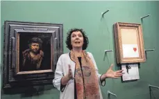  ?? FOTO: DPA ?? Christiane Lange, die Direktorin der Staatsgale­rie Stuttgart, steht vor dem geschredde­rten Banksy-Bild „Love is in the Bin“(rechts). Daneben hängt ein Selbstbild­nis von Rembrandt aus dem Jahr 1660.