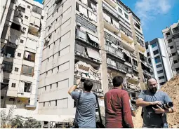  ?? BILAL HUSSEIN/AP ?? Journalist­s take pictures of the building that houses Hezbollah’s media office, which was damaged along with nearby buildings by what Lebanon says were Israeli drones.