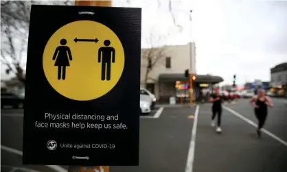  ??  ?? People jog past a social distancing sign in Auckland, New Zealand. Photograph: Fiona Goodall/Reuters