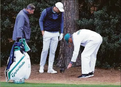  ?? David Cannon / Getty Images ?? Scottie Scheffler prepares to take a drop on the 18th hole during the third round of the Masters on Saturday.