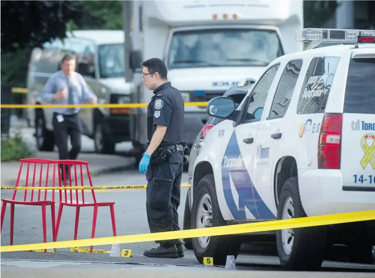  ?? TYLER ANDERSON / NATIONAL POST ?? A police officer passes two chairs marking evidence at the scene where a gunman shot more than a dozen people on Danforth Avenue in Toronto.