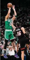  ?? Charles Krupa/Associated Press ?? Boston Celtics forward Jayson Tatum, left, shoots as Miami Heat forward Caleb Martin defends during the first half in Game 5 of the Eastern Conference finals on Thursday in Boston.