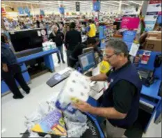  ?? ASSOCIATED PRESS ?? Walmart associate Javaid Vohar, right, checks out customers at a Walmart Supercente­r in Houston. Retailers will once again offer big deals and early hours to lure shoppers into their stores for the start of the holiday season. But they’ll also try to get shoppers out of their stores faster than ever by minimizing the thing they hate most: long lines.