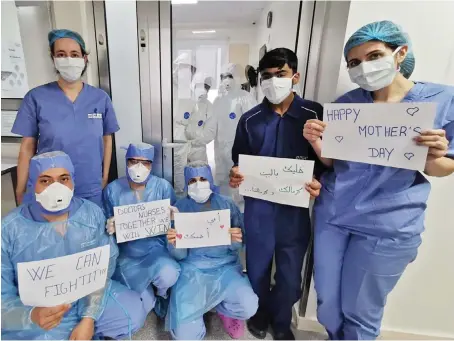  ?? AFP ?? Medical staff at a hospital in Beirut holding ‘Mother’s Day’ and other messages during a break in the coronaviru­s disease (COVID-19) section of the health facility.