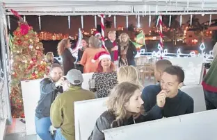  ?? MICHAEL LAUGHLIN/SUN SENTINEL ?? Sabrina Saada, Michael Miller, front, and other guests enjoy a cruise Wednesday along the New River and Intracoast­al Waterway during the Water Taxi Holiday Lights Cruise.