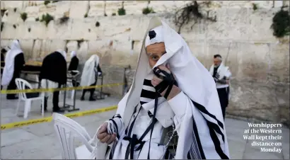  ??  ?? Worshipper­s at the Western Wall kept their distance on Monday