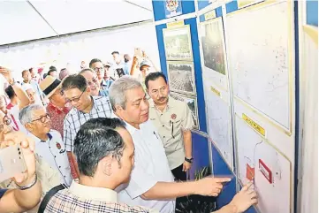  ??  ?? Awang Tengah (centre) looking at the plans of the Sadong Jaya village expansion project yesterday.