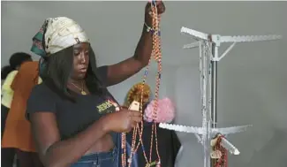  ?? ?? Renee Ayeh hangs waist beads on a rack for Jerk-N-Waisted.