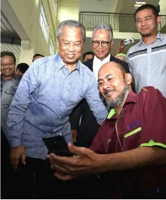  ??  ?? Muhyiddin (standing, left) joins Prof Madya Dr Zaidi Embong (seated, right) in a wefie shot during the former’s visit to Pagoh Higher Education Hub. — Bernama photo