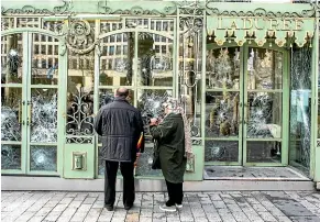  ??  ?? Bystanders take snapshots of the smashed windows of the famed tea salon Laduree on the Champs Elysees the day after it was vandalized during the 18th straight weekend of demonstrat­ions by the yellow vests, in Paris.