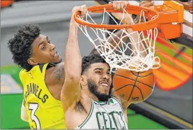  ?? Elise Amendola The Associated Press ?? Celtics forward Jayson Tatum dunks past Timberwolv­es forward Jaden Mcdaniels in the third quarter of Boston’s 145-136 overtime win Friday at TD Garden.