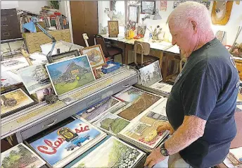  ?? Westside Eagle Observer/DANILE BEREZNICKI ?? Cecil Savage shows various prints of his artwork. Many have been featured in advertisem­ents for products such as PepsiCo. and Disney.