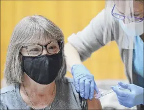  ??  ?? Adele Cramer, left, a nurse at Living Resources, receives the first dose of the Moderna COVID-19 vaccine from physician assistant Marjorie Schwab at the Schenectad­y County Public Library on Thursday.