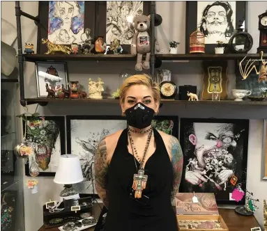  ?? ANDREW CASS — THE NEWS-HERALD ?? War Paint Studios owner Sarah Beans stands in front of artwork at her Willowick tattoo shop after nearly two months away. Tattoo shops were permitted to reopen in Ohio May 15.