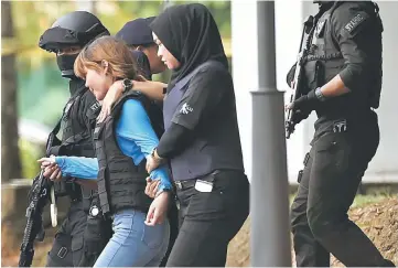  ??  ?? Vietnamese Doan Thi Huong, who is charged with the murder of Kim Jong Nam, is escorted by police as she leaves Sepang court. — Reuters photo