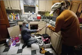  ?? TONY GUTIERREZ — THE ASSOCIATED PRESS FILE ?? Handyman Roberto Valerio, left, hands homeowner Nora Espinoza the broken pipe after removing it from beneath her kitchen sink in Dallas on Feb. 21. The pipe broke during freezing temperatur­es brought by last week’s winter weather.