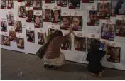  ?? PETROS GIANNAKOUR­IS — THE ASSOCIATED PRESS, FILE ?? A woman touches photos of Israelis missing and held captive in Gaza, displayed on a wall in Tel Aviv on Oct. 21.