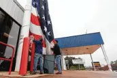  ?? ?? Volunteers prepare a 100-pound, 30-foot-tall, 60-foot-long American flag for the dedication.