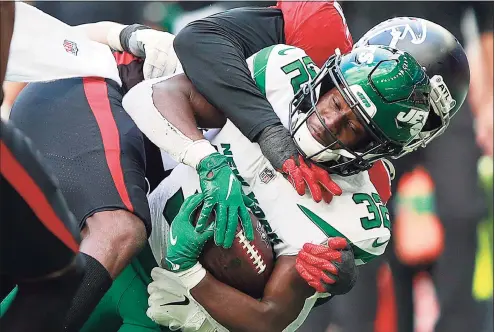  ?? Ian Walton / Associated Press ?? New York Jets running back Michael Carter (32) is tackled during the first half against the Atlanta Falcons at the Tottenham Hotspur stadium on Sunday in London.