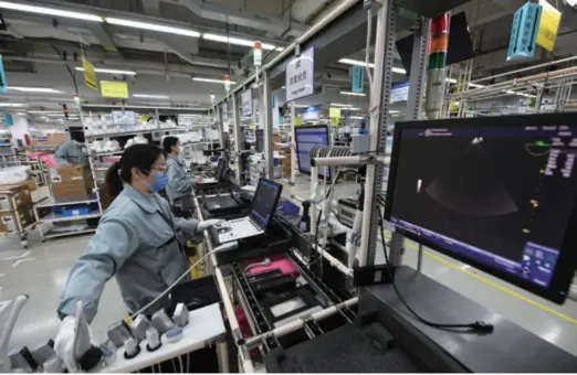  ??  ?? Staff members work on a production line that makes ultrasound machines at the GE Healthcare plant in Wuxi, Jiangsu Province in east China, on February 15