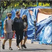  ?? FRANCINE ORR Los Angeles Times ?? SARAH TINDALL, center, walks with her sons, Dylan and River, past a homeless encampment near Larchmont Charter School in Hollywood last month.