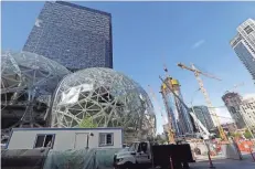  ?? ASSOCIATED PRESS ?? Large spheres take shape in front of an existing Amazon building as new constructi­on continues across the street in Seattle this month. For years now, much of downtown Seattle has been a maze of broken streets and caution-taped sidewalks. Some say the...