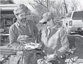  ?? PAUL A. SMITH / MILWAUKEE JOURNAL SENTINEL ?? Muche offers duck poppers to Schultz after a morning of duck hunting on Horicon Marsh.