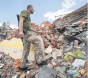  ?? ANDRII MARIENKO AP ?? On the outskirts of Kharkiv, Ukraine, on Tuesday, a Ukrainian serviceman looks at the rubble of a school that was destroyed days ago by a missile strike.