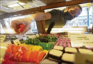  ?? ROBERT F. BUKATY/AP ?? Beth Duckworth fills a display cabinet with sweet treats at The Goldenrod, a popular restaurant and candy shop, Wednesday in York Beach, Maine. The business is looking to hire 30 to 40 more workers in addition to the 70 or so it now employs.