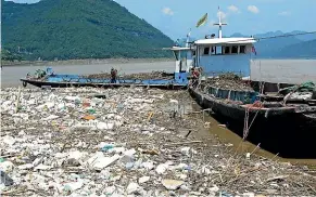  ?? GETTY IMAGES ?? Workers collect floating rubbish on the Yangtze River in Chongqing. China’s economic boom has created mountains of waste, but the country has no real recycling system, relying instead on an informal network of ‘‘trash pickers’’ to sift through the rubbish and extract anything of value.