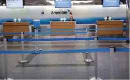  ?? (Reuters) ?? AN AMERICAN AIRLINES agent stands at an empty check-in counter at LaGuardia Airport in New York last month.